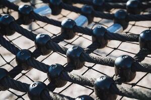 A detailed closeup view capturing a vibrant playground climbing net, featuring robust black ropes and colorful plastic nodes for fun photo