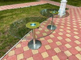 Two elegantly designed glass tables are meticulously arranged on a strong and durable brick sidewalk, forming a visually striking and appealing setup amidst the surrounding environment photo