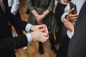 A man in formal wear shares a playing card gesture with a group at an event photo