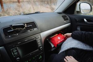 A person is currently seated inside a vehicle, specifically a car, which contains a first aid kit conveniently placed within the glovebox compartment for easy access during emergencies photo