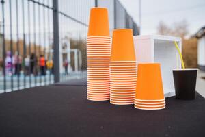 Three distinct stacks of vibrant orange cups are currently resting on a wooden table, adding a pop of color to the setting while also creating a visually appealing arrangement photo