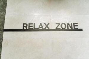 A Relax Zone sign on the floor is a key part of the buildings branding, adding to the ambiance with a unique design and message, fostering a welcoming atmosphere for visitors and patrons photo