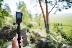 A person is using a gimbal stabilizer to hold an action camera in the scenic outdoors. The setting is perfect for capturing nature and wildlife with modern technology photo