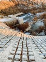 A beautifully designed brick walkway that seamlessly leads to a serene river nestled within the stunning mountains in the distance, presenting a scenic view of natures splendor photo