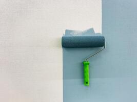 A paint roller is actively in use at this moment to efficiently apply paint onto the surface of a wall, which ensures that there is an even and seamless finish along with vibrant color hues photo