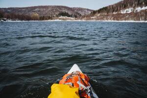 SUP board floats on the river against the background of mountains, rafting on a spring river in high water, things are in a protective bag, hiking on the lake. photo