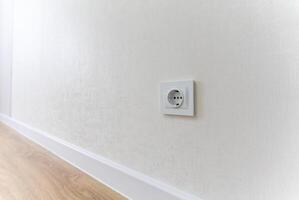 On the wall of the room, there is a clearly visible white electrical outlet that provides a convenient point of connection for various electronic devices and household appliances as needed photo