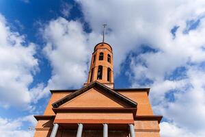 As I gazed upward at a tall brick building that features a stunning bell tower, I couldnt help but admire its intricate architecture and the beauty of the clear blue sky behind it photo