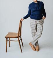 This is an elegant casual outfit featuring a cozy sweater paired with stylish checked trousers, all showcased in a sophisticated studio setting photo