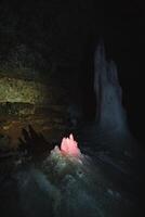 Within the depths of a mysterious cave, a captivating pink crystal is illuminating the surrounding darkness, creating a magical atmosphere that enchants all who venture near it photo