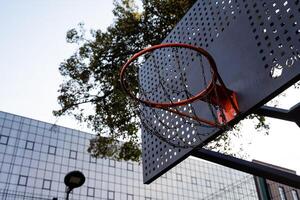 A vibrant urban basketball hoop stands out against the backdrop of modern architectural structures in the city photo