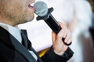A man in a suit is singing into a microphone at a musical event photo