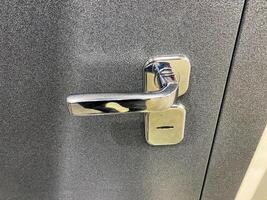 This image presents a detailed closeup view of a door handle attached to a door, showcasing the intricate design and materials used in this important fixture of vehicles and buildings photo