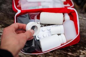 A person is holding a bandage in front of a first aid kit, indicating a readiness to provide assistance for emergency situations or injuries that may occur during various activities photo