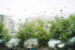 The raindrops on the car window enhance the view, adding to the beauty of the trees in the background, creating a picturesque natural landscape with a touch of tranquility and freshness photo