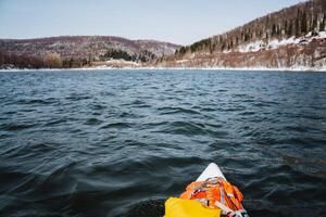 Panorama of a mountain river, rafting on a board with a paddle, things lying on the bow of the boat, spring in the mountains, a lake at a height. photo