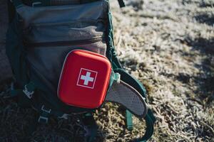 A red first aid kit in a hard case, a travel first aid kit, a red cosmetic bag with a white cross. photo