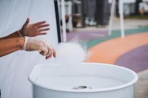 An individual dressed in protective gloves is skillfully preparing cotton candy using a specialized machine designed for this sweet treat. Its a delightful process to observe in action photo