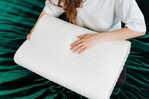 The lady cradles a memory foam pillow in a lavish setting, creating a tranquil and snug environment on lush green velvet. Its an opulent and serene place for relaxation photo