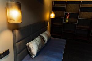 The bedroom features a comfortable bed and a stylish wallmounted lamp, creating a cozy atmosphere that beckons relaxation and rest, perfect for unwinding after a long day photo