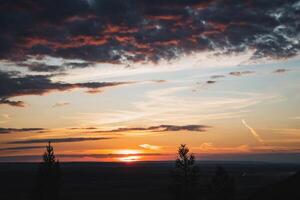 Experience the breathtaking beauty of a stunning sunset casting vibrant colors over rolling hills, creating a tranquil evening landscape photo