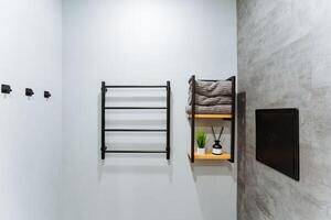 The bathroom features a welldesigned towel rack along with a shelf, providing ample storage and convenience. It harmonizes the elements of comfort and functionality in interior spaces photo