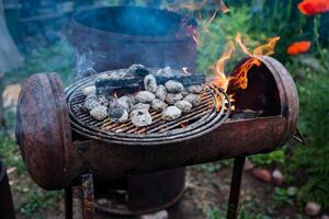 A barrel repurposed as a BBQ grill is being used to cook food outdoors, serving its purpose well by preparing tasty meals. The grill is a versatile cooking tool for meat and other cuisine photo