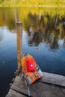 A wellloved, worn backpack sits on a solid dock that stretches out over a calm and tranquil lake, which is surrounded by peaceful nature and the soothing sounds of flowing water nearby photo