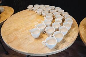 A beautifully crafted wooden table that features an assortment of empty coffee cups arranged neatly in rows, showcasing a minimalist yet inviting aesthetic for any setting photo
