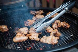 Chicken wings sizzle on the grill, expertly flipped for even cooking. Outdoor grilling enhances flavor, creating a mouthwatering dish. Enjoy the process and delicious result photo