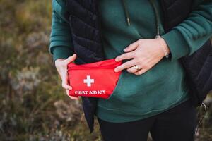 A person is gripping a first aid kit tightly in their hands, implying that they might be equipped for an emergency situation, thus ensuring safety and preparedness at all times as needed photo