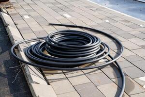 A coiled black hose is strategically positioned on a paved surface at a bustling construction site for various purposes photo