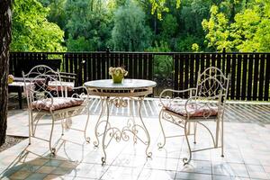 A table and chairs on a patio with trees in the background photo