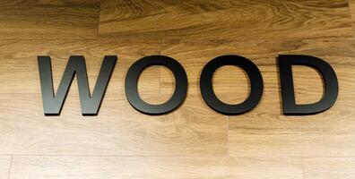 The word Wood is displayed on a background made of wood, accompanied by related elements such as font, hardwood, wood stain, flooring, plank, circle, brand, number, and rectangle photo