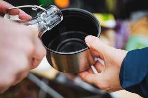 A person is very carefully pouring water into a cup that is sitting on the table, taking their time to fill it perfectly to avoid spills or splashes, ensuring that no mess is made at all photo