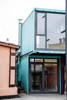 A modern building constructed using shipping containers features numerous windows that allow plenty of natural light to enter, enhancing the overall aesthetic appeal and functionality photo
