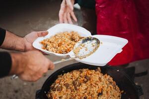 A person is handing over a delicious plate of food to another individual, sharing a moment of nourishment and care, showcasing the importance of meals in human connection photo