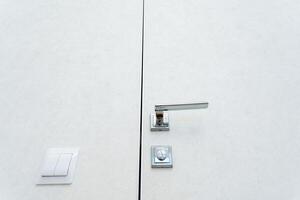 A comprehensive description of a door with a handle and light switch typically seen in homes. It showcases elements like the handle, switch, and material details in a residential setting photo