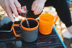 A person is skillfully and carefully pouring water into a cup that is placed on an ordinary table, demonstrating a simple yet essential action that many individuals engage in daily life photo