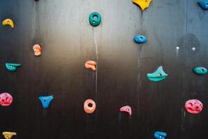 A truly remarkable climbing wall showcases a stunning variety of colorful rocks, which together create a warm and vibrant atmosphere that appeals to both climbers and onlookers alike photo