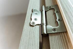 This image showcases a closeup of a securely attached door hinge on a sturdy wooden door, highlighting exceptional craftsmanship and highquality materials in its design photo