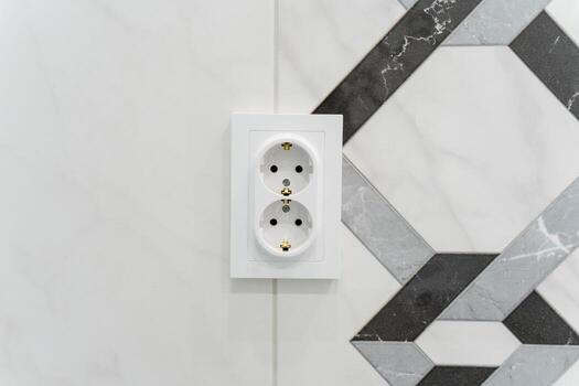 This image shows a closeup of a white electrical outlet on a tiled wall, emphasizing its thoughtful design, placement, and functionality, blending aesthetics with practicality photo