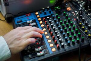 Sound engineer manipulating knobs on mixing console for audio mixing at event photo