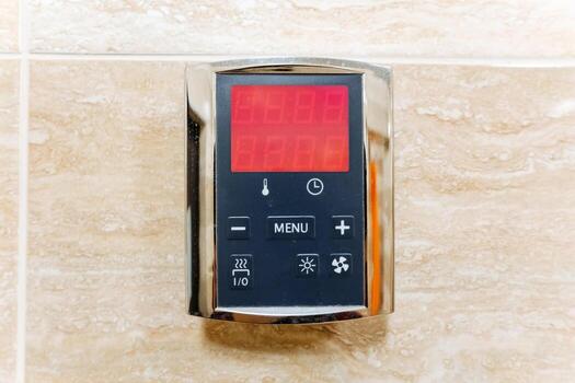 A modern digital thermostat has been securely mounted on a beautifully tiled wall, offering an efficient and convenient way to control the temperature within the entire space effectively photo