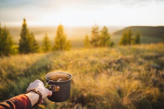 Embracing the Dawn Experiencing a Serene Morning with Coffee in the Great Outdoors, surrounded by nature and tranquility, is simply blissful photo
