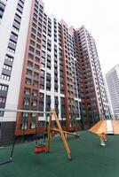 A large, multistory building that stands prominently in the area, with a playground situated in front of it, offering a space for children to play and enjoy recreational activities photo