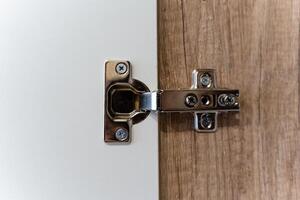 This closeup image vividly displays a modern cabinet hinge that is securely attached to a stylish wooden door design photo