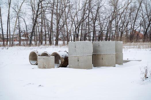 A beautifully captured snowy landscape showcases stark concrete structures alongside trees situated in the background, creating a tranquil and serene atmosphere photo