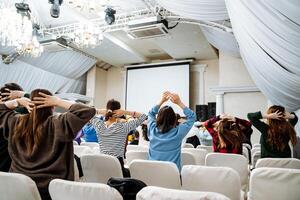 Crowd in chairs watching projector screen during event photo