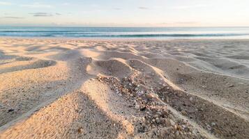 Golden Sandy Beach Waves Textured Patterns With Pebbles At Sunrise Ocean Horizon And Soft Sky photo